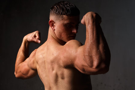 Athlete bodybuilder trains in the studio in the rain.の写真素材