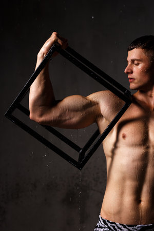 Athlete bodybuilder trains in the studio in the rain.の写真素材