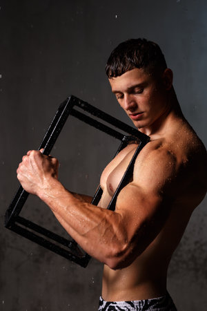 Athlete bodybuilder trains in the studio in the rain.の写真素材