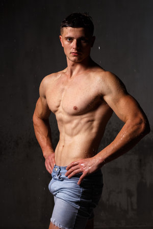Athlete bodybuilder trains in the studio in the rain.の写真素材