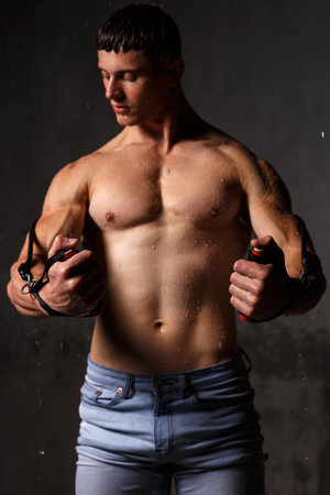 Athlete bodybuilder trains in the studio in the rain.の写真素材