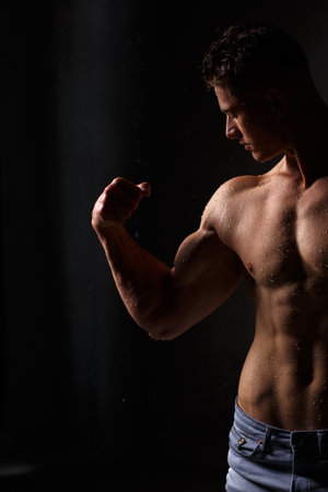 Athlete bodybuilder trains in the studio in the rain.の写真素材
