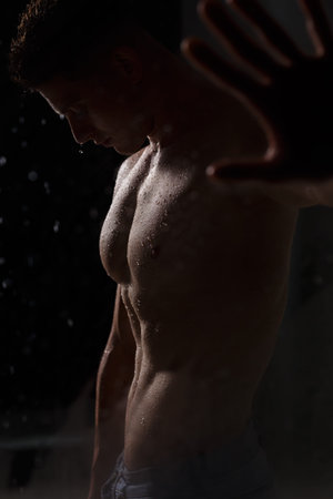Athlete bodybuilder trains in the studio in the rain.