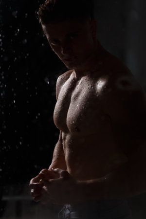 Athlete bodybuilder trains in the studio in the rain.の写真素材