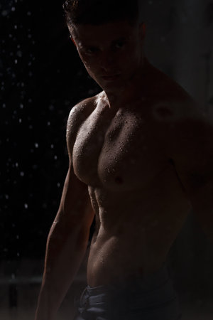 Athlete bodybuilder trains in the studio in the rain.の写真素材