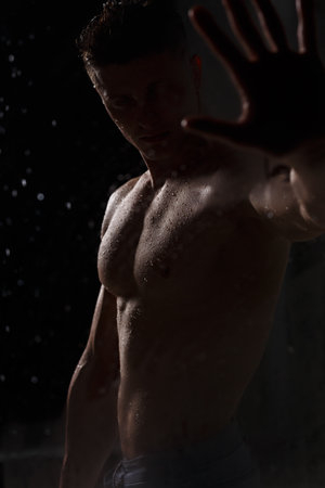 Athlete bodybuilder trains in the studio in the rain.の写真素材