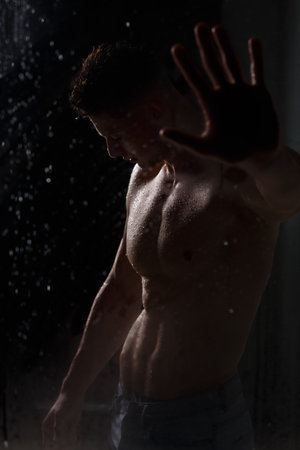 Athlete bodybuilder trains in the studio in the rain.の写真素材