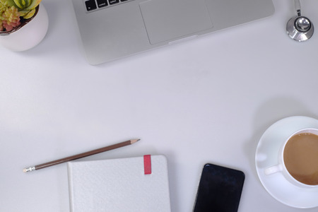 op View of trendy White Office Desk with white Cropped Laptop and green Flowerの写真素材