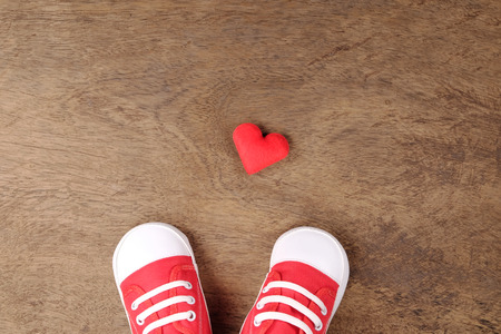 Baby shoes with red hearts on wooden backgroundの写真素材