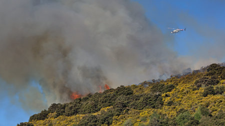 Helicopter patrolling bush fire above Outram Glen, Otago, New Zealand
