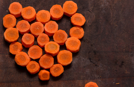 On a wooden table laid out pieces of carrot in the form of heart.の写真素材