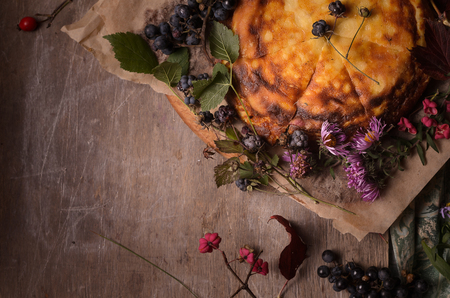 On a wooden table autumn composition from flowers, berries and yellow cake.の写真素材