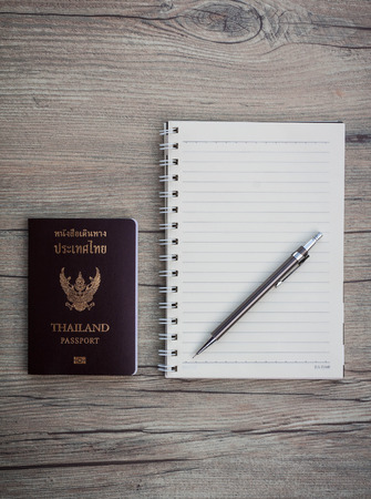 Thailand passport with notebook and pen on brown table wood.の写真素材