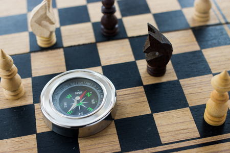 Wood chess and compass on old wood chessboard of  business direction strategy conceptの写真素材