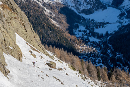 A male hiker walking over snowfield and looking at the background of Chamonix valley below.の写真素材