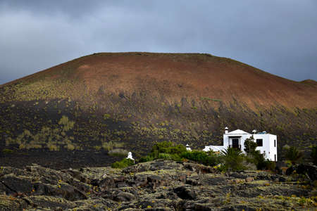 Beautiful volcanic landscape with a white house in front. Lanzarote, Canary Islands, Spain. Image taken from public ground.の写真素材