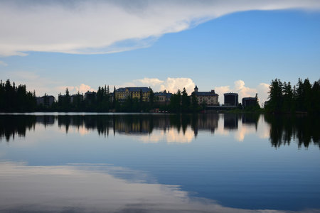 Strbske pleso, lake and small town, in the evening. Buildings and trees reflecting in the water....