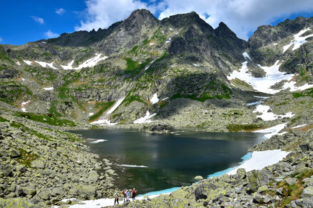 Lake Velke Zabie pleso in the High Tatra Mountains. Some hikers walking on a trail. Slovakia.