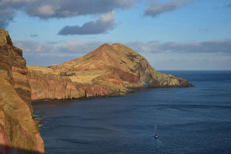 Bright colors at sunset at the peninsula Ponta de Sao Lourenco, the easternmost point of Madeira, Portugal. The visitor center Casa do Sardinha is surrounded by palm trees. A boat approaching the gate in the rocks.の写真素材