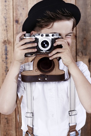 Young boy taking photograph with old cameraの写真素材