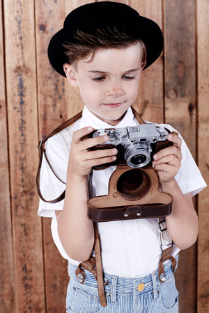 Young boy looking at old cameraの写真素材