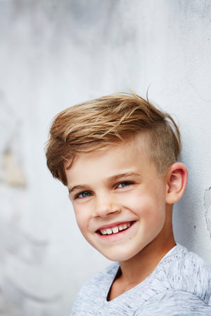 Portrait of young boy leaning against wallの写真素材