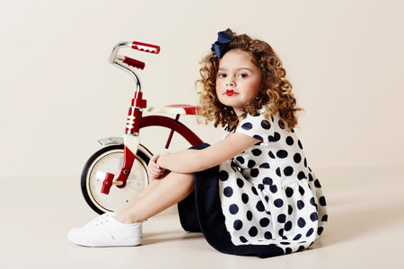 Retro girl in spotty dress with tricycle, portraitの写真素材