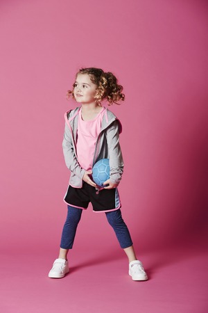 Young girl holding football, looking awayの写真素材