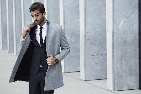 Smooth businessman in coat, looking awayの写真素材