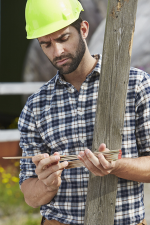 Worker measuring with ruler, looking downの写真素材