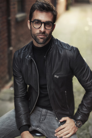 Cool guy posing in glasses and leather jacketの写真素材