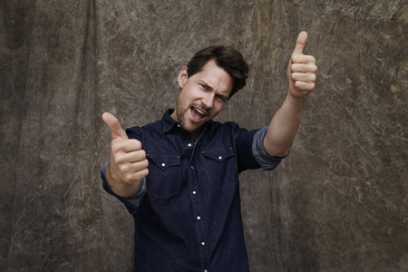 Portrait of man giving thumbs up, studioの写真素材