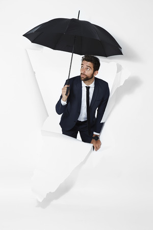 Businessman ready for rain with umbrellaの写真素材