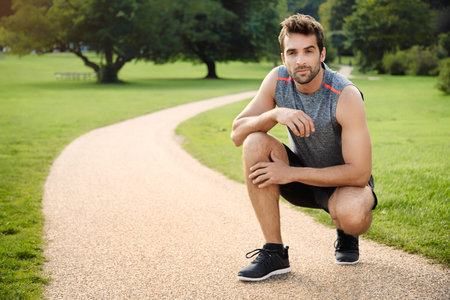 Athlete crouching in park, portrait