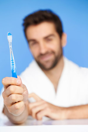 Man holding toothbrush, studioの写真素材