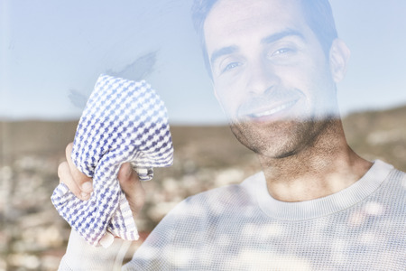 Domestic dude cleaning window, portraitの写真素材