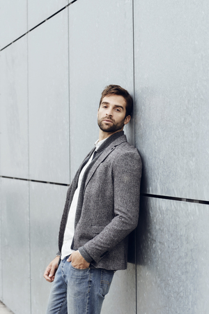 Leaning guy on grey wall, portraitの写真素材