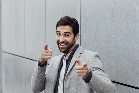 Smiling guy pointing fingers, portraitの写真素材