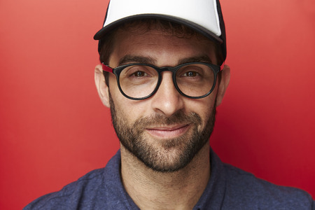 Smiling man in cap and glasses, portraitの写真素材