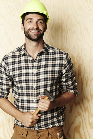 Hard hat wearing handsome man holding hammerの写真素材