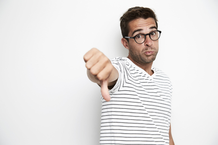 Thumbs down dude in white studio, portraitの写真素材