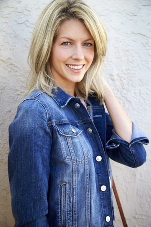 Beautiful woman in denim jacket smiling to cameraの写真素材