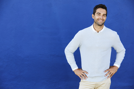 Blue sweater dude smiling against blue wall, portraitの写真素材