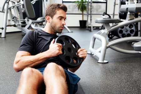 Guy performing sit ups with weight in gym