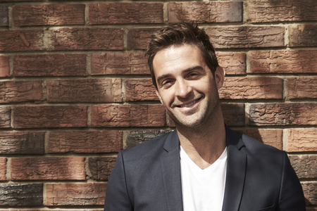 Portrait of handsome man smiling in suit jacket, outdoorsの写真素材