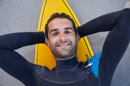 Surf guy relaxing on board on beach, portrait