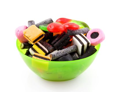 Green plastic bowl with different kind of candy isolated on white backgroundのeditorial素材