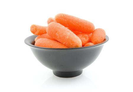 Fresh raw carrots in black bowl isolated on white backgroundの写真素材