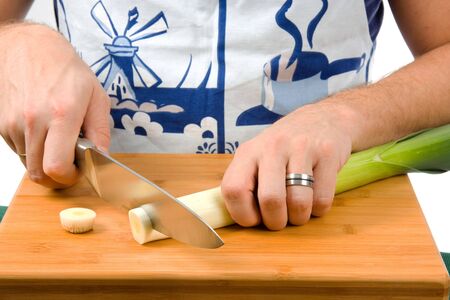Cook is cutting leek on board in closeupの写真素材