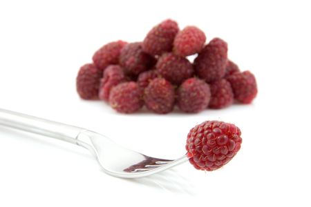 delicious fresh raspberries, one on a fork and a pile in the back, over white backgroundの写真素材